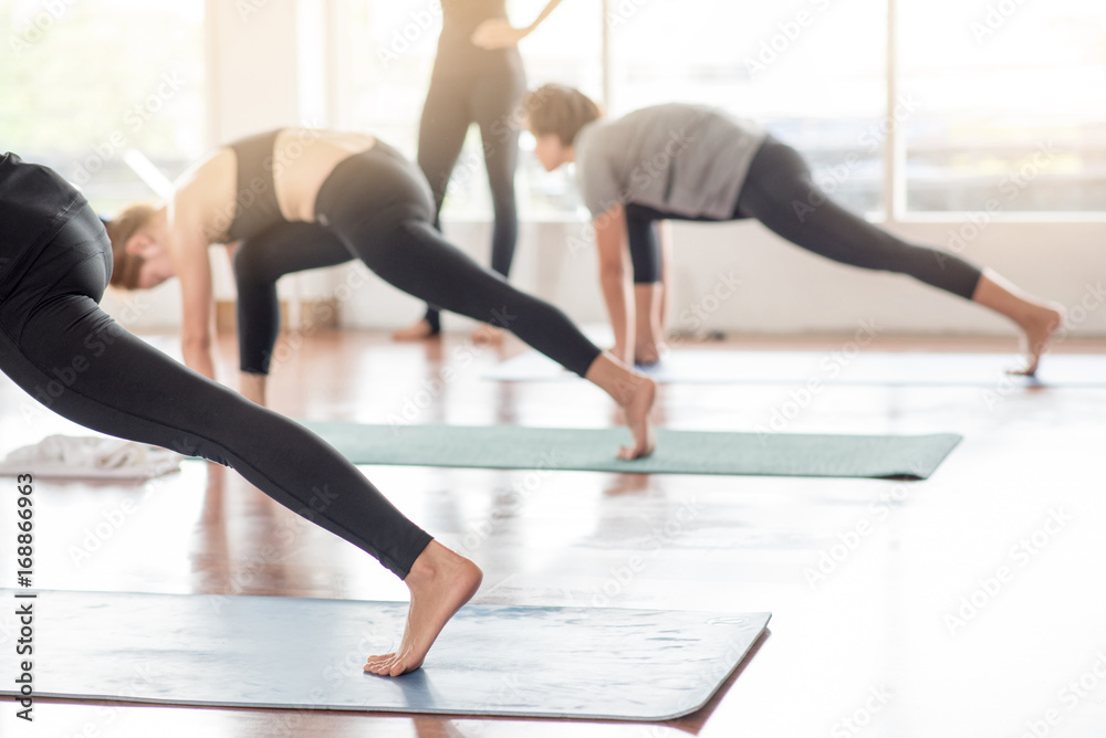 Group women stretching and practices yoga in a class in a gym