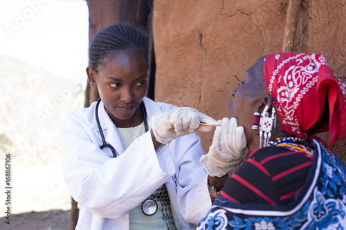 Doctor examining patient in Maasai village. Kenya, Africa photo