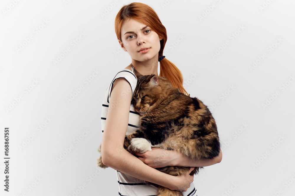 Young woman on a light background holds a maine coon cat, empty space for copy, portrait