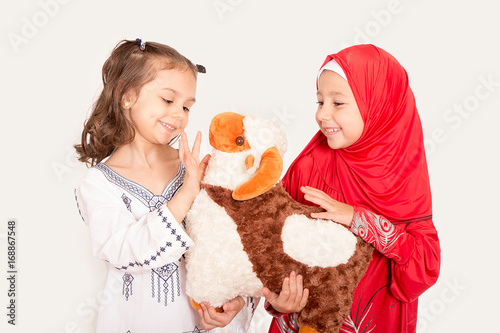 Happy little Muslim girls playing with sheep toy - celebrating Eid ul Adha - Happy Sacrifice Feast photo