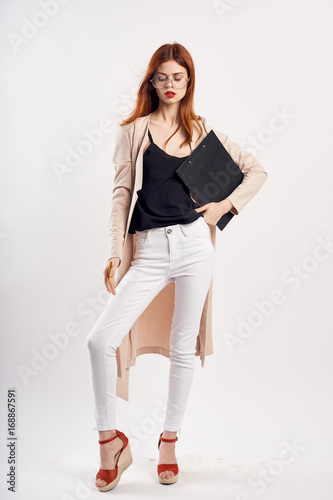 Young woman with glasses on a light background holds documents in full growth, fashion, style, beauty © SHOTPRIME STUDIO