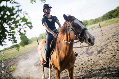 Portrait of young woman riding horse in countryside
