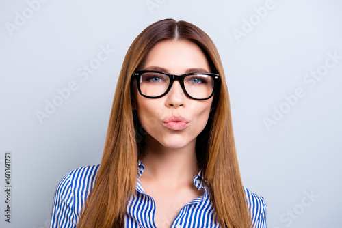 Kiss for you! Success and beauty concept. Close up of playful young business lady in formal wear, standing at the pure background isolated with pouted lips