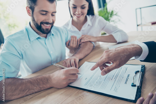 Please sign here. Happy couple is buying new house, lawyer is presenting contract to sign, they are in his office, cheerful and well dressed