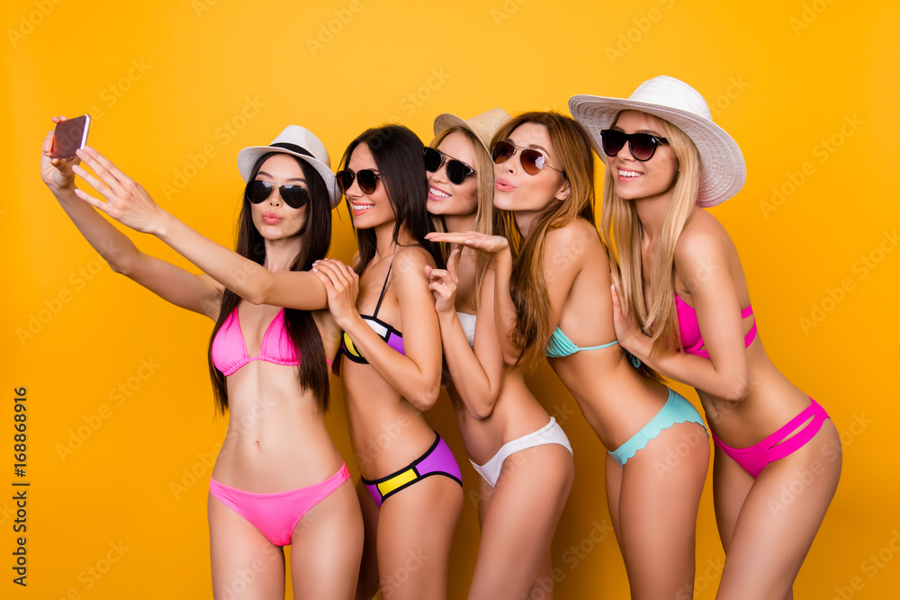 Selfie time, ladies! Five girlfriends in cool swim suits, sunglasses and caps are posing for a selfie photo shot, that brunette is taking. They are gesturing, making memories, enjoying near the pool Selfie time, ladies! Five girlfriends in cool swim suits, sunglasses and caps are posing for a selfie photo shot, that brunette is taking. They are gesturing, making memories, enjoying near the pool