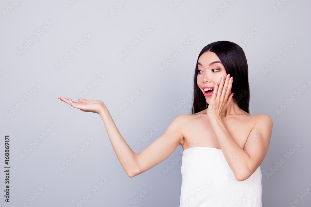 Young amazed cute korean lady is presenting the innovational product in beauty and health industry, copy space in her hand on grey background Young amazed cute korean lady is presenting the innovational product in beauty and health industry, copy space in her hand on grey background