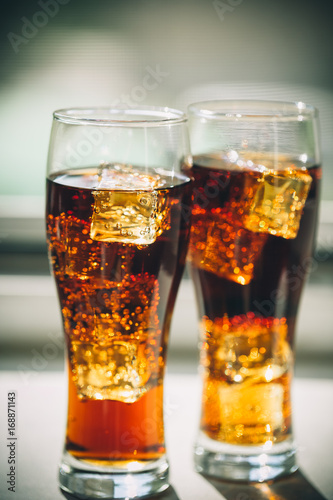 Beautiful cold drink of Cola with ice cubes in a glass on a grey window background with free space. Shallow DOF.