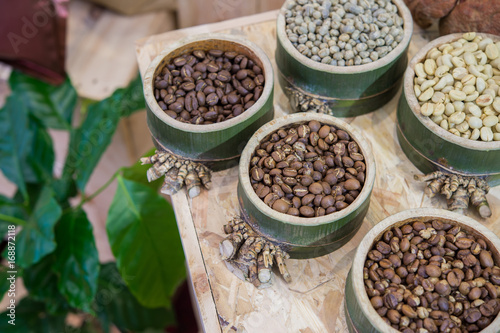 Coffee beans in bamboo tray on brown wooden background