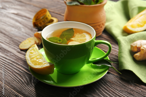 Cup of tea with lemon and ginger on wooden table. Weight loss concept