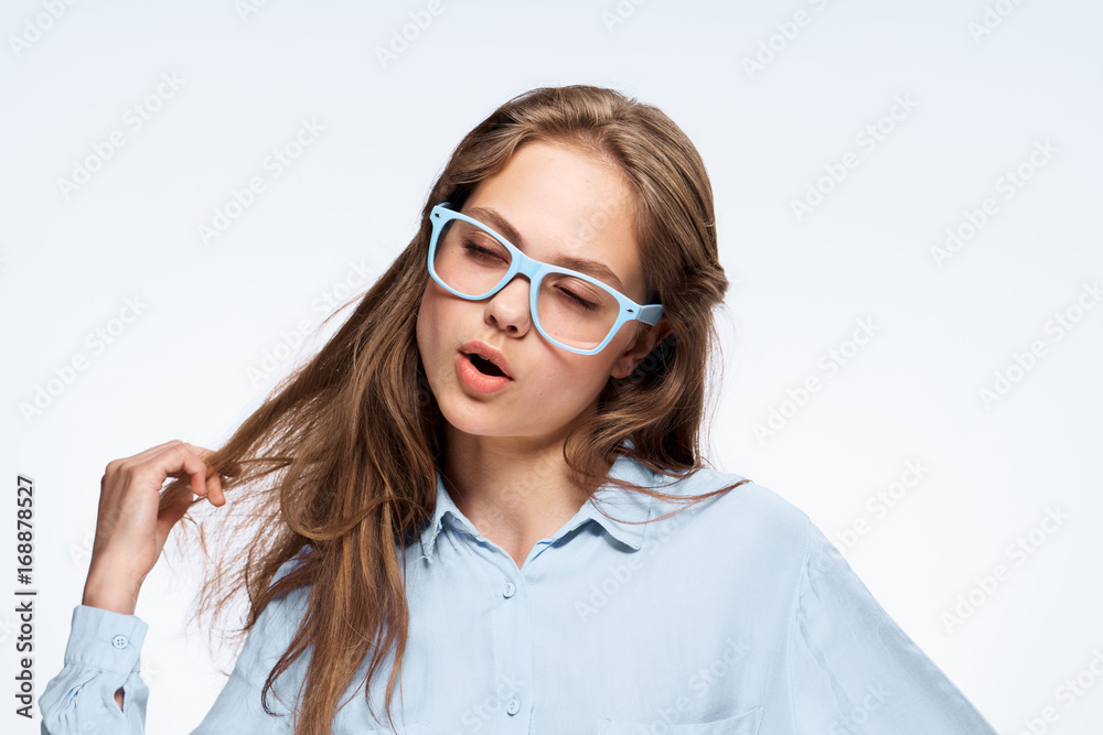 Young woman in blue glasses on white isolated background holds her hair, portrait Young woman in blue glasses on white isolated background holds her hair, portrait