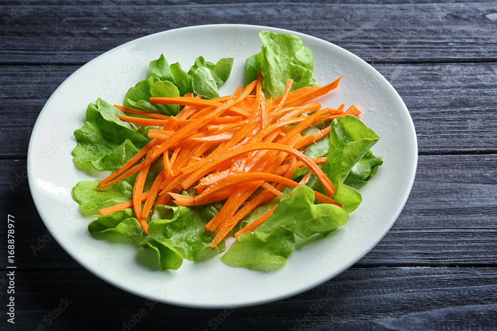 Plate with delicious carrot salad on wooden table Plate with delicious carrot salad on wooden table