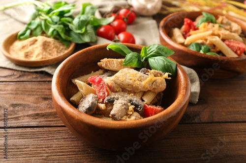 Bowl with delicious turkey tetrazzini and ingredients on wooden table