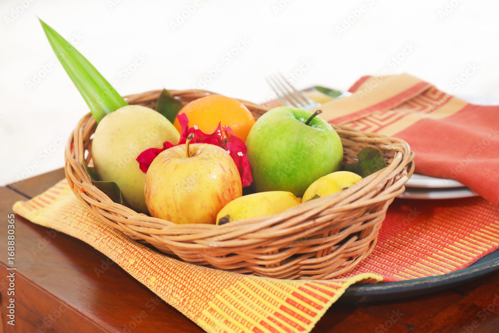 Wicker bowl with fresh fruits for breakfast on table