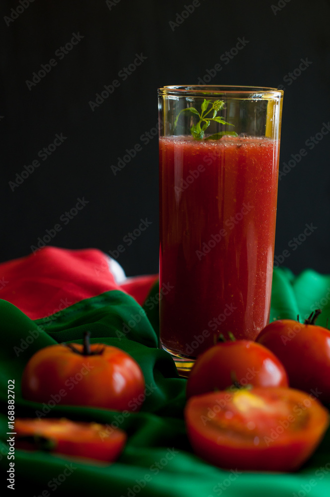 Glass and bottle of tomato juice with vegetables and green napkin on wooden background Glass and bottle of tomato juice with vegetables and green napkin on wooden background
