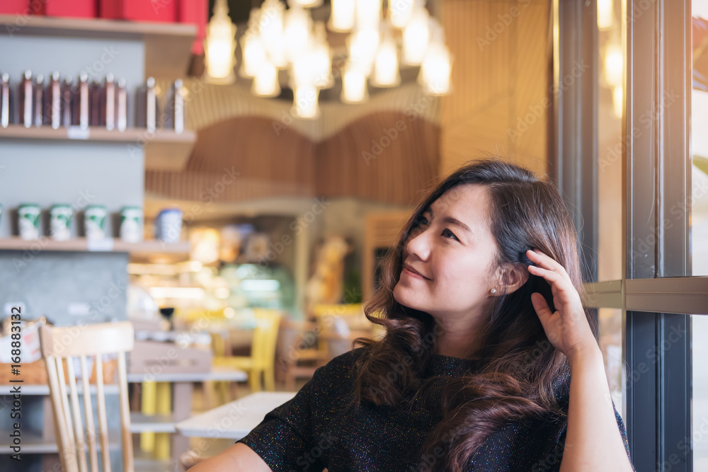 Closeup portrait image of a smiley beautiful Asian woman with feeling good sitting and relaxing in modern cafe Closeup portrait image of a smiley beautiful Asian woman with feeling good sitting and relaxing in modern cafe