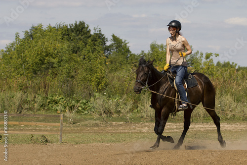 Women is horse riding - red hair girl in summer meadow