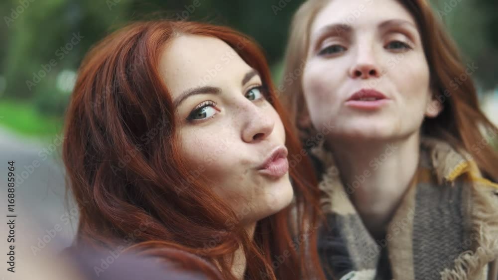 Redhead Friends taking selfie with a smart phone and making faces and fun. 20s