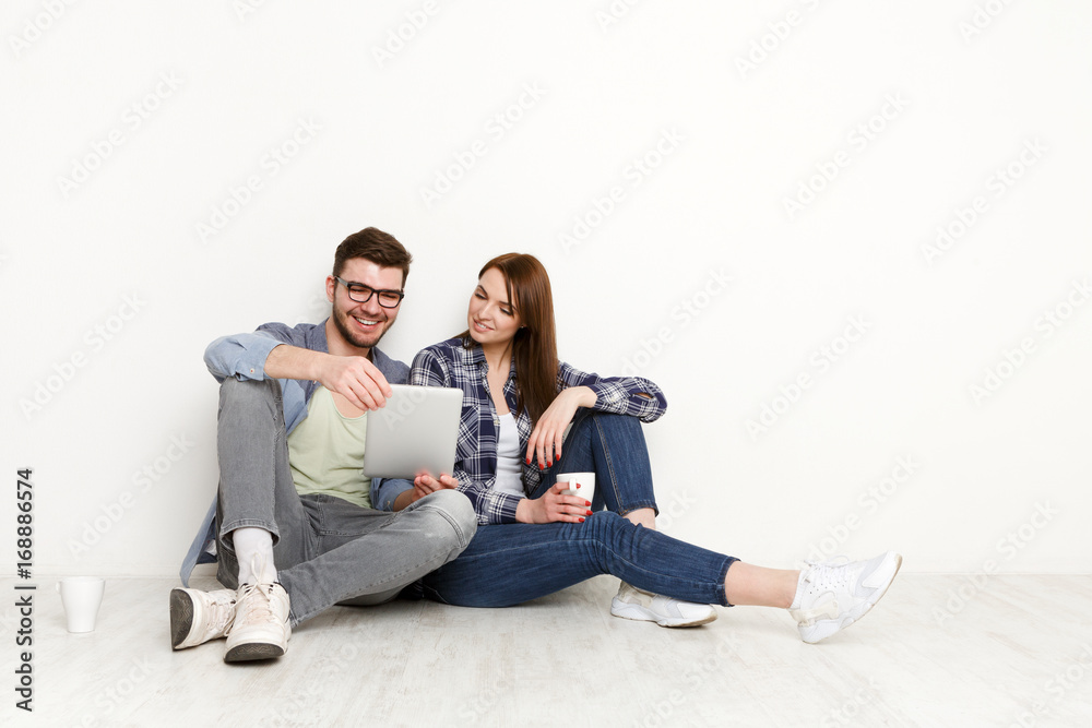 Happy couple shopping online, sitting on floor at home Happy couple shopping online, sitting on floor at home