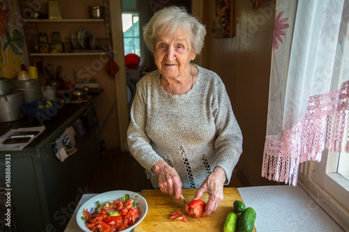 Obraz na płótnie An elderly woman prepares a meal in a village house. w salonie