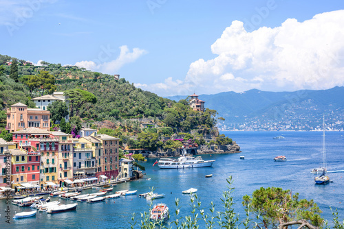 Beautiful aerial daylight view from top to ships on water and buildings in Portofino city of Italy. Tourists walking on sidewalk. Top view