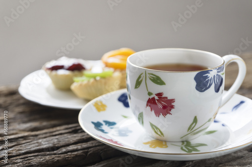 A cup of tea and fruit tarts on the table