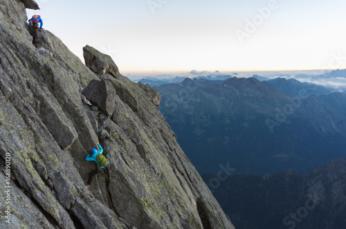 Alpinists rock climbing on a high summit with panoramic sideview