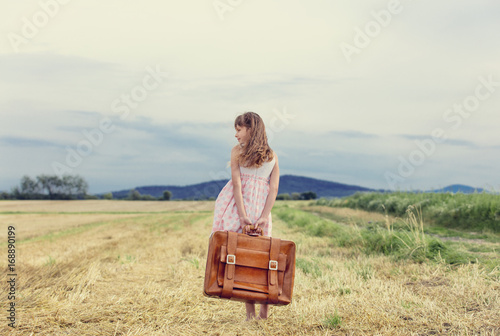 Little girl in classic dress with travel suitcase