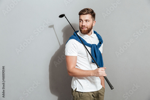 Bearded Smiling golfer posing in studio with club in hand