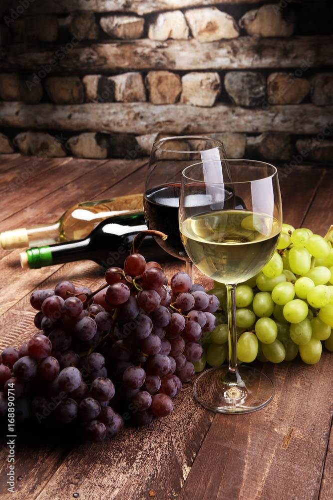 Red Wine bottle and white wine with grapes and glasses on wooden