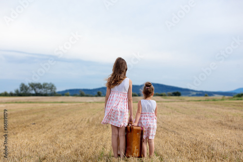 Two Little girls in classic dress holding suitcase