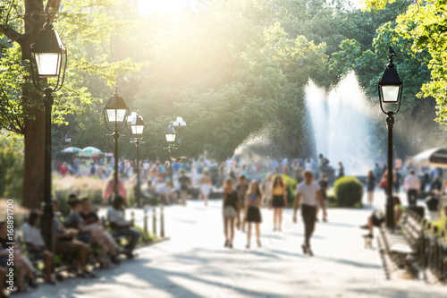Obraz na płótnie Anonymous crowds of people walking in Washington Square Park in New York City with the glow of sunlight shining in the background w salonie