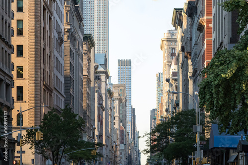 View down Fifth Avenue in Manhattan, New York City with historic buildings lining both sides of the street in NYC