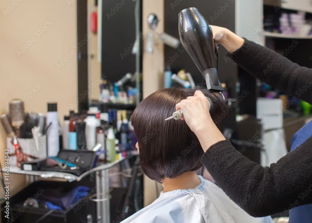 The hairdresser dries her hair a brunette girl in a beauty salon. The hairdresser dries her hair a brunette girl in a beauty salon.