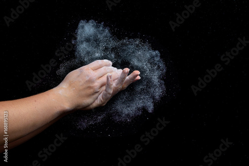 Female climber chalks her hands with white chalk.