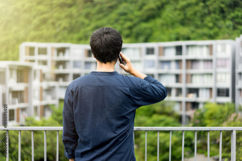 A man talking on smart phone for business looking on building through the balcony. Always stay connected concept A man talking on smart phone for business looking on building through the balcony. Always stay connected concept