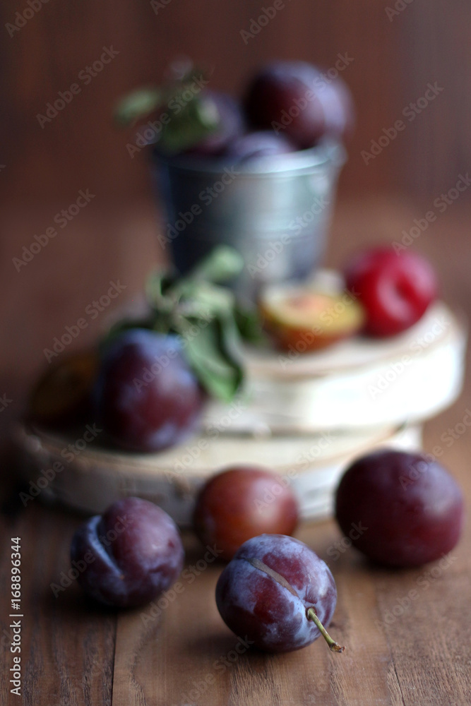 Plums in a small bucket on a wooden background