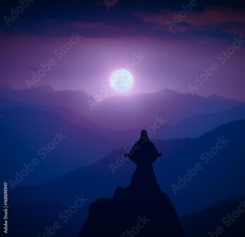 Silhouette of human in a moonlight meditating