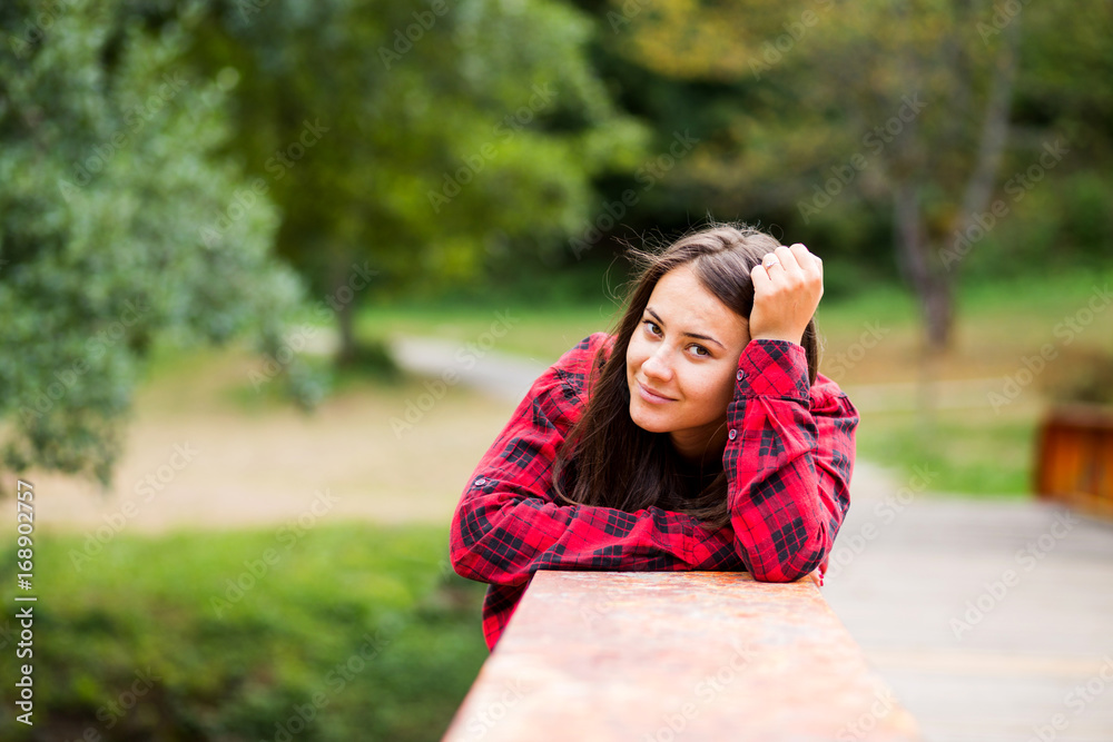 Beautiful young female wearing plaid shirt laying on the side of the bridge Beautiful young female wearing plaid shirt laying on the side of the bridge