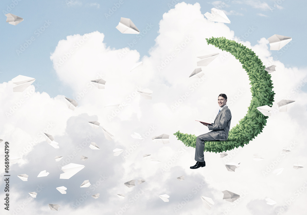 Businessman or student sitting on green moon and reading book Businessman or student sitting on green moon and reading book