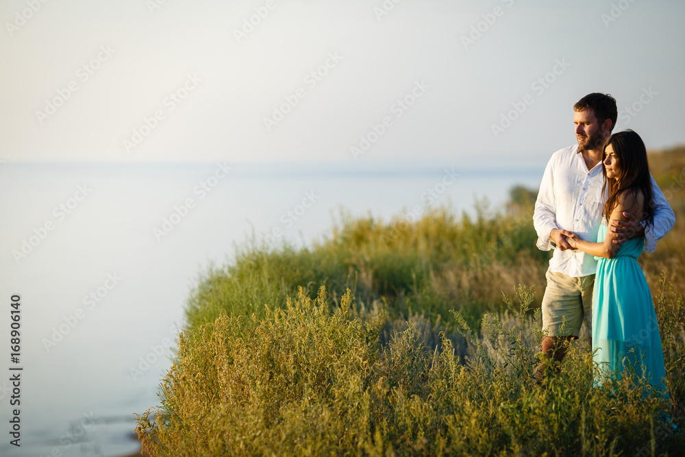 Lovers Man and woman are looking into the distance, the couple are holding hands near the river or lake shore, the couple are standing in the tall grass