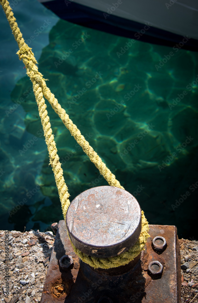 Naklejka premium Metal bollard and rope securing a ship