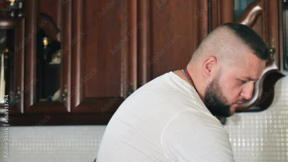 The portrait of bearded muscular man is cooking at the kitchen The portrait of bearded muscular man is cooking at the kitchen