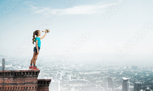 Concept of careless happy childhood with girl dreaming to become pilot