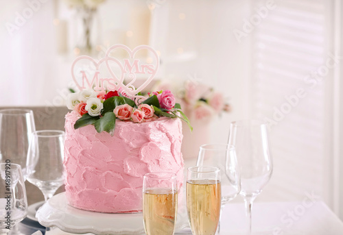 Beautiful served table with glasses of champagne and delicious cake for lesbian wedding