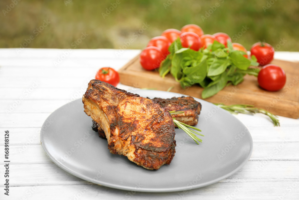 Plate with tasty grilled steaks on table