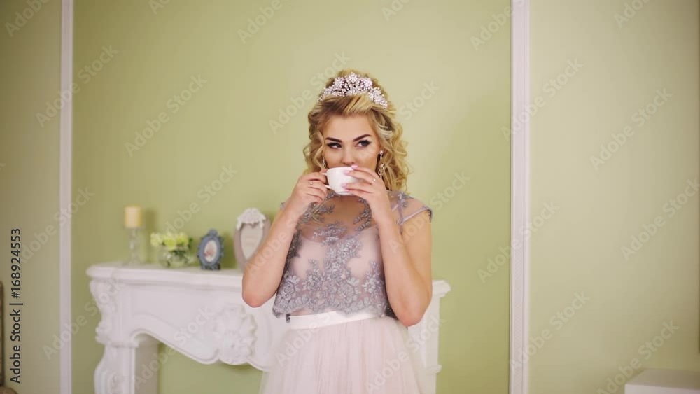 Bride takes a cup of coffee from the mantelpiece and takes a sip. Bride takes a cup of coffee from the mantelpiece and takes a sip.