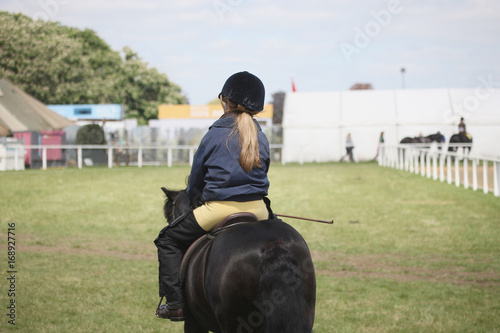 A girl in a jockey uniform riding a pony © Anna Jurkovska