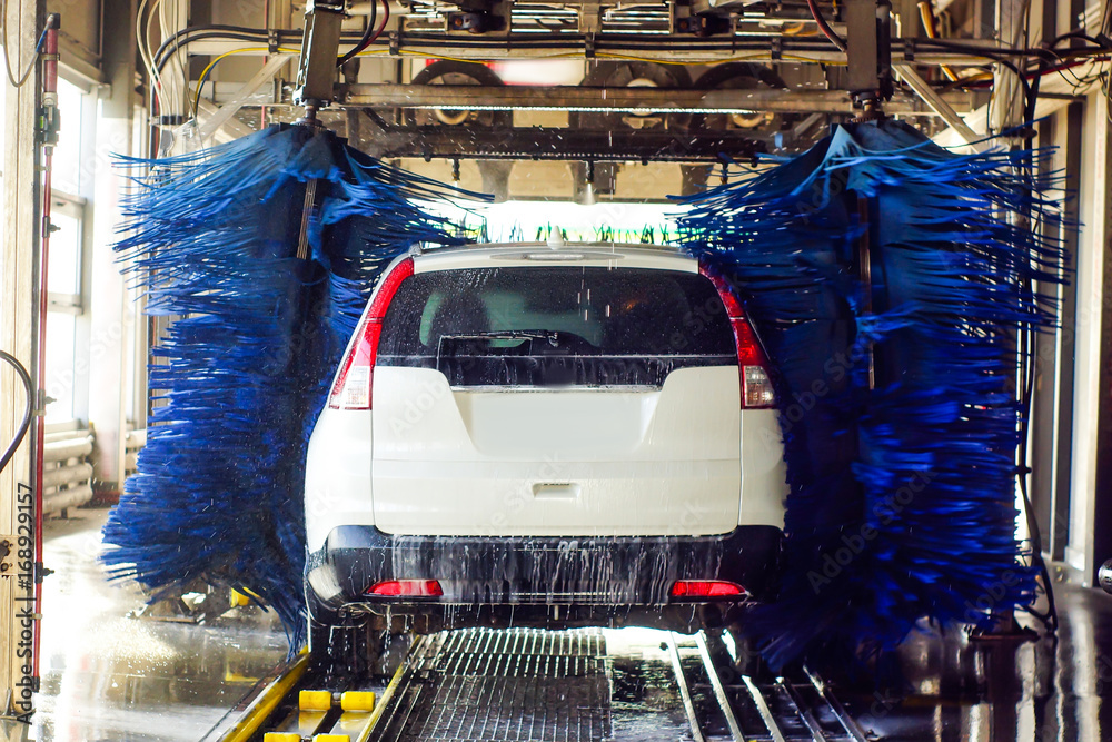 Foto Stock Car wash, black car in automatic car wash, rotating red and