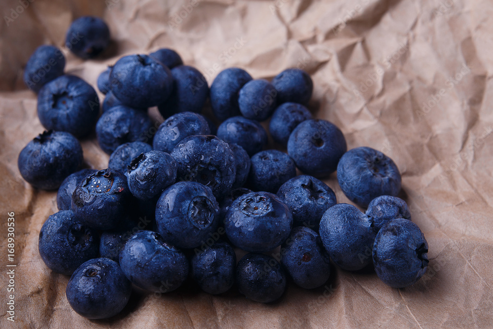 Blueberries on rustic wooden background, close up. Delicious berries on craft paper, macro Blueberries on rustic wooden background, close up. Delicious berries on craft paper, macro