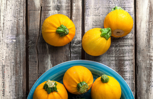 Yellow zucchini overhead group on blue plate and old rustic white wooden table in studio